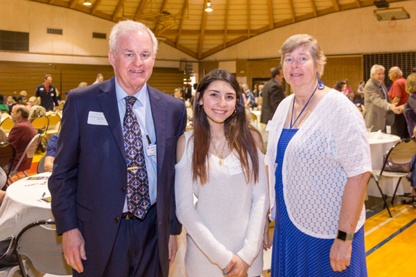 Dr. Gary E. Wilson and Diane Wilson standing with COM student scholarship recipient Elodia Mejia
