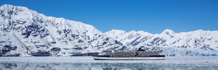 Cruise ship in icy water surrounded by snowy mountains