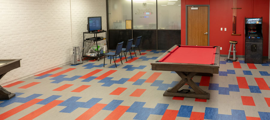 Student recreation room showing a pool table, arcade game, and video game station.
