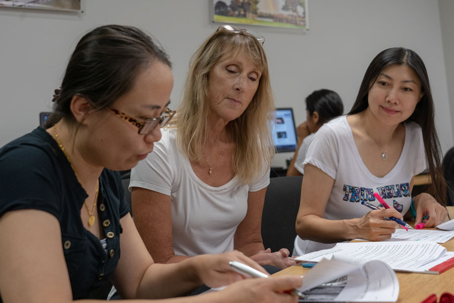 Tutor helping two students with writing assignments
