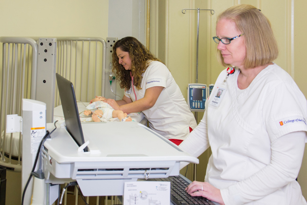 College of the Mainland nursing students Ana Herrera, left, assesses a robotic baby that can mimic symptoms while student Meredith Hood documents it in the health record.