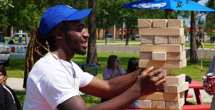 Student playing a giant sized jenga game outside at an event.