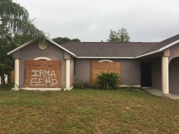 Photo of boarded up house with the text IRMAGERD spray painted on the boards.